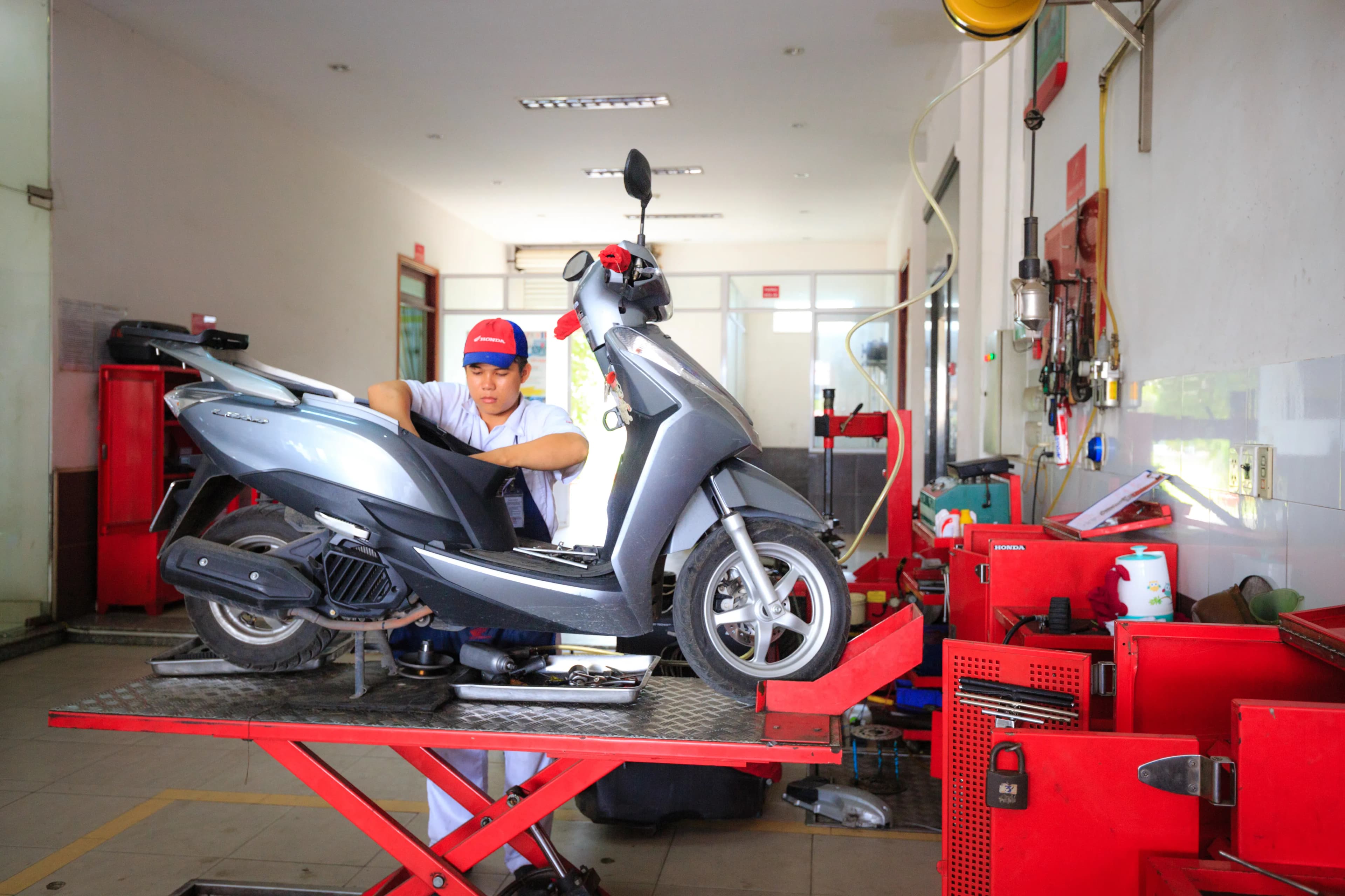 Kapalı bir tamirhanede motosiklete bakım yapan usta